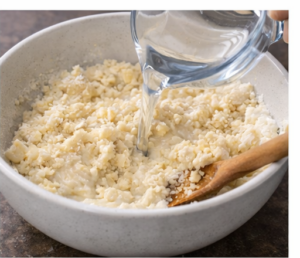 Pouring water into a mixing bowl of ingredients